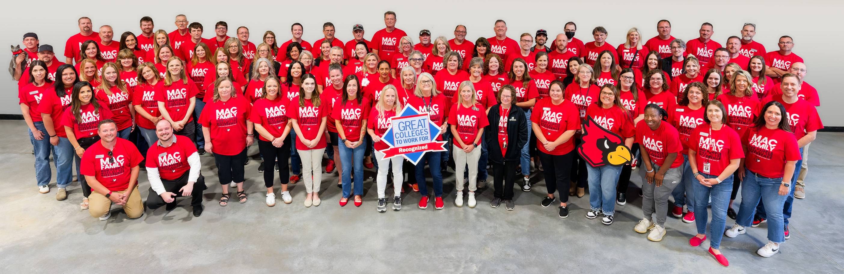 Group photo of employees wearing matching red t-shirts and holding Great Colleges to Work For sign